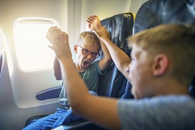 Two naughty boys travelling by plane. The boys are fighting and yelling. Naughty kids are a nightmare for their parents and other passengers. 