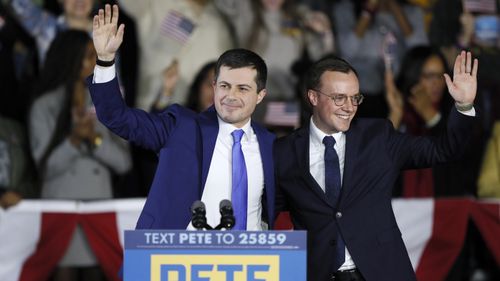 Mayor Pete Buttigieg and his husband Chasten, right, wave to supporters.