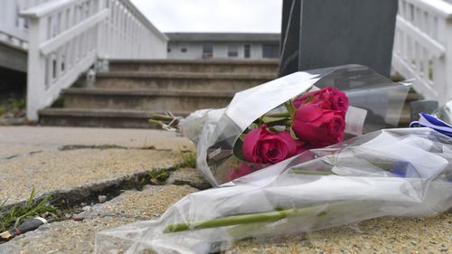 Flowers rest near an entrance to the Gabriel House assisted living facility, Monday, July 14, 2025, following a fire that started late Sunday and resulted in multiple fatalities, in Fall River, Mass. (AP Photo/Steven Senne)