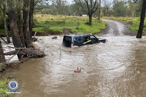 Three people rescued by police officer from car stuck in floods in NSW Hunter region.