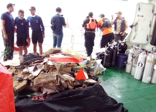 Rescuers collect bodies of plane crash victims in a bag on the Indonesia Search And Rescue boat.