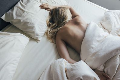 Top view of a young blonde woman sleeping on her bed in the morning.