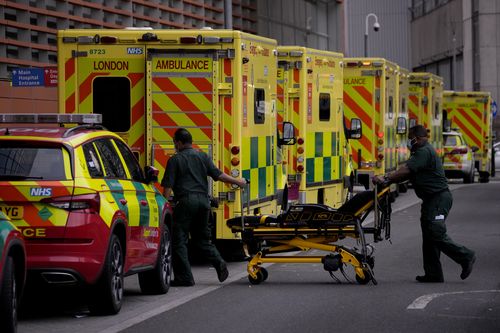 Paramedics push a trolley next to a line of ambulances outside the Royal London Hospital in the Whitechapel area of east London, Thursday, Jan. 6, 2022. 