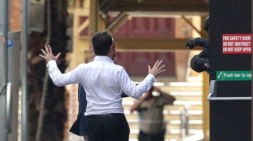 One of the first hostages to escape raises his hands as he approaches armed police. (Getty)