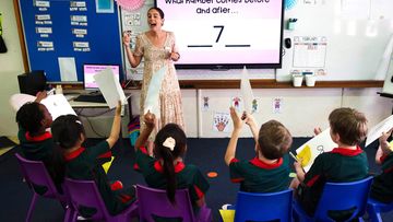 A class of primary school children listen to their teacher.