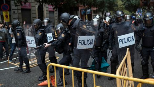 Spanish riot police removes fences thrown to them as one aims his rubber bullet rifle as they try to prevent people from reaching a voting site at a school assigned to be a polling station by the Catalan government in Barcelona, Spain. (AP)