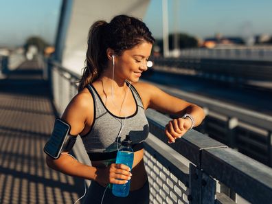 Female runner taking a break from running workout and reviewing info on her smart watch.