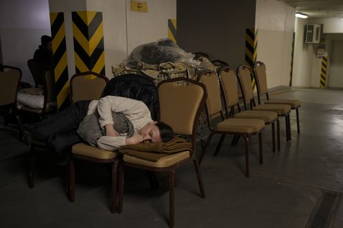 A woman sleeps on chairs in a hotel underground parking turned into a bomb shelter during an air raid alert in Kyiv, Ukraine, Sunday, Feb. 27, 2022. Terrified men, women and children sought safety inside and underground, and the government maintained a 39-hour curfew to keep people off the streets as more than 150,000 Ukrainians fled to neighboring countries and the United Nations warned the number could grow to 4 million if fighting escalates.(AP Photo/Vadim Ghirda)