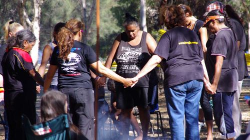 Aboriginal women gather around a fire at a “tent embassy” at Heirisson Island in Perth in 2012. (AAP)