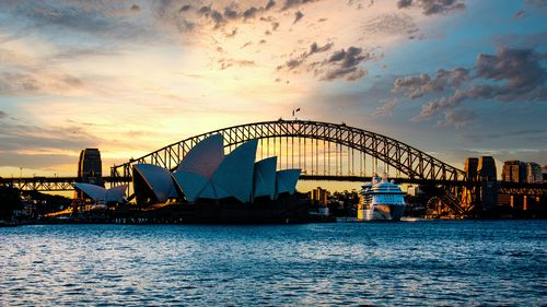 Color Photograph of the Sydney Opera House and Sydney Harbor Bridge at sunset with a cruise ship leaving Circular Quay