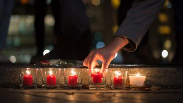 Mourners light candles for those whose lives were lost in the Paris attacks. (AAP)