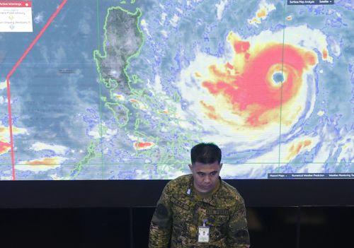 A member of the Philippine Air Force stands in front of a satellite image of Typhoon Mangkhut, locally named Typhoon Ompong, at the National Disaster Risk Reduction and Management Council operations centre in Manila.