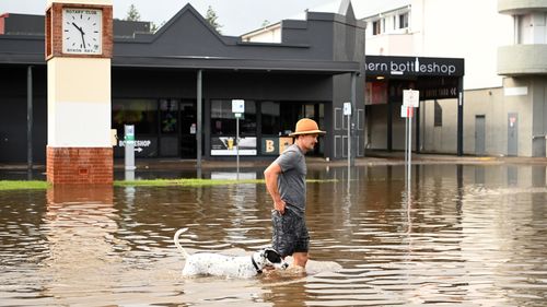 A man and his dog walk through floodwater on March 30, 2022 in Byron Bay, Australia. Evacuation orders have been issued for towns across the NSW Northern Rivers region, with flash flooding expected as heavy rainfall continues. It is the second major flood event for the region this month. (Photo by Dan Peled/Getty Images)