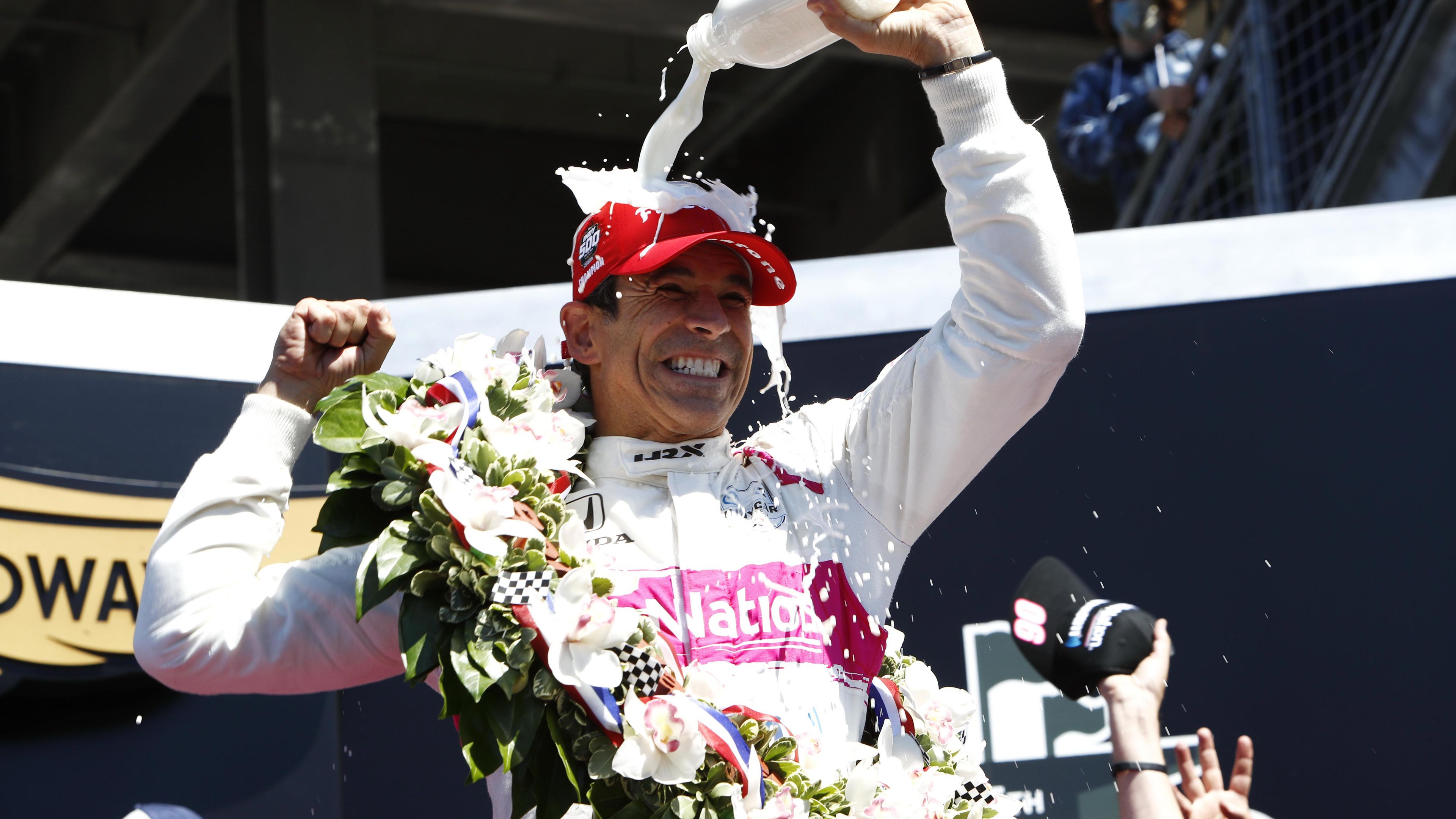 Helio Castroneves pours the traditional winner&#x27;s milk over his head.