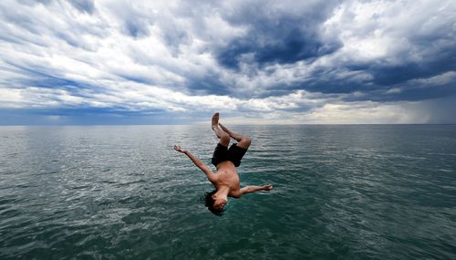 Hara Tera, 13,  leaps off the Frankston Pier as the storm clouds approach during warm seasonal weather in Melbourne. (AAP) 