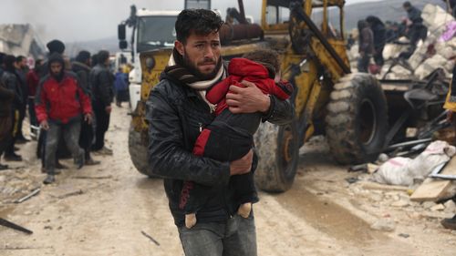 A man carries the body of an earthquake victim in the Besnia village near the Turkish border, Idlib province, Syria, Monday, Feb. 6, 2023. 