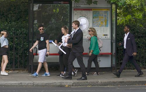 Mężczyzna trzyma wachlarz, gdy wychodzi przed Parlament w Londynie, wtorek, 12 lipca 2022 r. 