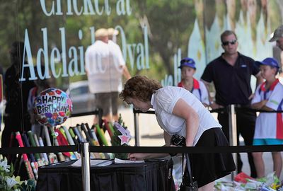 A woman signs a book of condolences at Adelaide Oval.