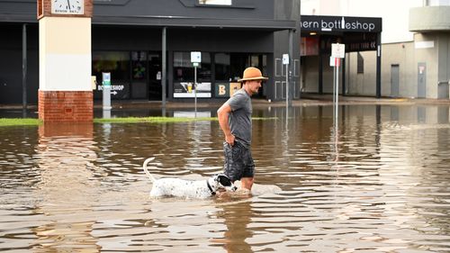 A man and his dog walk through floodwater on March 30, 2022 in Byron Bay, Australia. Evacuation orders have been issued for towns across the NSW Northern Rivers region, with flash flooding expected as heavy rainfall continues. It is the second major flood event for the region this month. (Photo by Dan Peled/Getty Images)