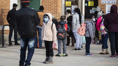 Parents and children line up outside George B. Armstrong International Studies Elementary School as students return to in-person learning at the Rogers Park neighbourhood school on the North Side, of Chicago. 