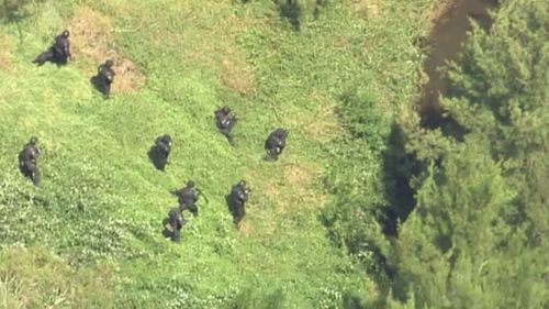 Heavily armed police converge on the graveyard where the second man's body was found. (9NEWS)
