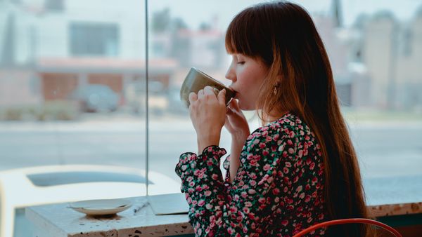 Stock photo of woman drinking coffee at a cafe.