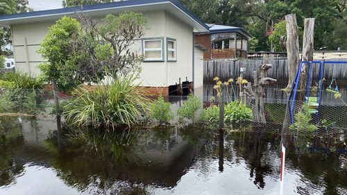 The front and backyards of a house in Lake Conjola on NSW's south coast are filled with floodwaters. 