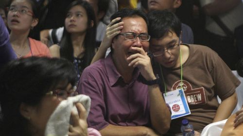 Relatives of passengers aboard the AirAsia flight weep upon seeing the news on television. (AAP)