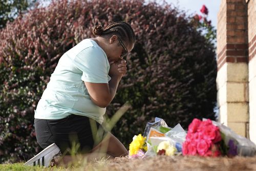 Linda Carter, of Grayson, Ga., kneels near Apalachee High School to place flowers as she mourns for the slain students and teachers 