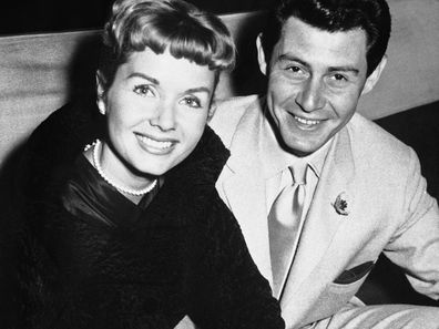 File- This June 4, 1957, file photo shows Eddie Fisher and his wife Debbie Reynolds attending the reception at the Prince of Wales Theater, London. Reynolds herself has likened their split to the Jennifer Aniston-Angelina Jolie-Brad Pitt triangle, telling Vanity Fair last year: "My three husbands all left me for another woman and obviously I wasn't a very sexual lady."  (AP Photo/File)