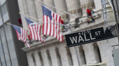 The Wall St. street sign is framed by American flags flying outside the New York Stock Exchange in New York