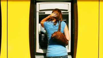 A man and woman withdraw money from a Commonwealth Bank ATM