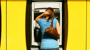 A man and woman withdraw money from a Commonwealth Bank ATM