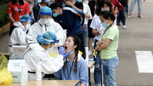 Employees line up for medical workers to take swabs for the coronavirus test at a large factory in Wuhan in central China's Hubei province Friday, May. 15, 2020. Wuhan have begun testing inhabitants for the coronavirus as a program to test everyone in the Chinese city of 11 million people in 10 days got underway.  (Chinatopix Via AP) CHINA OUT
