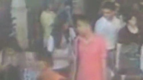 A CCTV image of two suspected accomplices in red and white shirts.