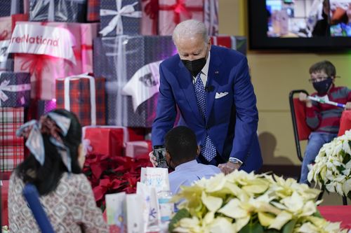 President Joe Biden shows a photo of Commander, a purebred German shepherd puppy and the newest member presidential family, to a patient at Children's National Hospital in Washington, Friday, Dec. 24, 2021. 