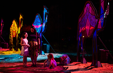 Parrtjima 2021: A young family view the 'Merging Kultcha' installation, a train of five, towering, illuminated camels.