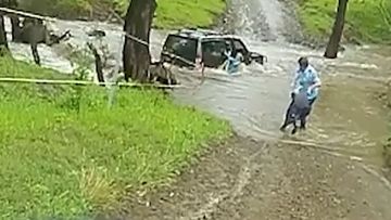 A police officer has rescued three people from a car stranded in floodwaters