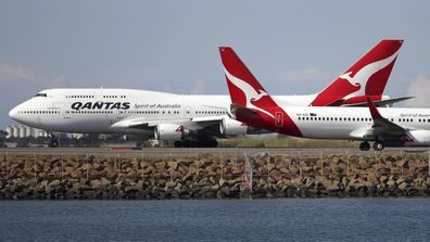 Qantas planes taxi on the runway at Sydney Airport.