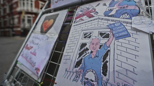 Posters featuring character of the WikiLeaks founder are fixed on a barrier in front of the Ecuadorian embassy. (AAP)