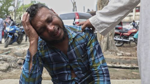 Un uomo non identificato piange per i parenti che hanno ricevuto i corpi delle vittime di un incidente stradale dopo che un autobus è caduto in un fosso lungo la strada nel distretto di Chapchar del distretto di Madaripur, Bangladesh, domenica 19 marzo 2023.