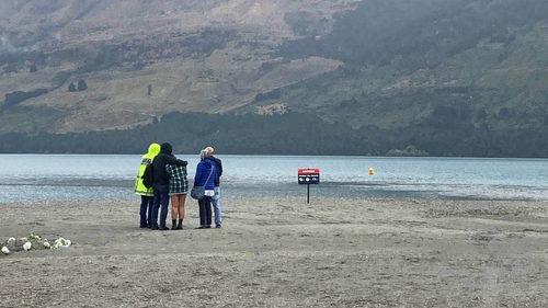 Les parents, le frère et le fiancé de Jonathan Jordan Young regardent les plongeurs de la police chercher son corps dans le lac Wakatipu.