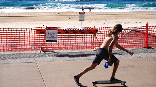 A skateboarder passes a closed section of Surfers Paradise Beach on the Gold Coast