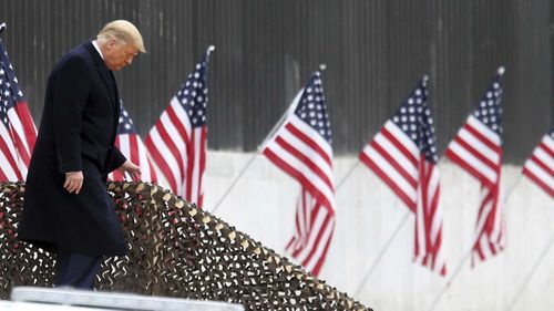 President Donald Trump walks down the steps before a speech near a section of the U.S.-Mexico border wall.