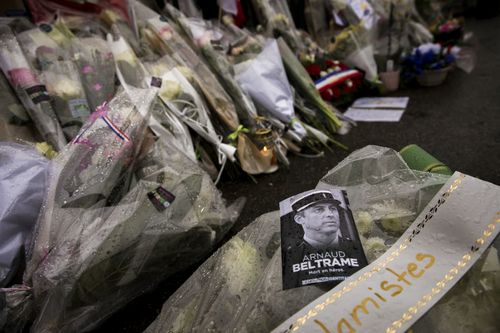 A photo of Arnaud Beltrame placed on a bunch of flowers at the main gate of the Police headquarters in Carcassonne. (AAP)