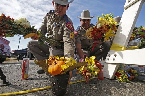 Texas State Troopers pick up flowers left for a memorial to move them out of the street near the church while investigators work at the scene of the mass shooting. (AAP)