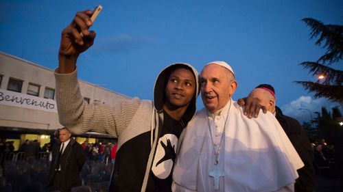 Pope Francis stopped for selfies with people at the refugee shelter outside of Rome on Holy Thursday. (AAP)