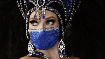 A showgirl in a face mask stands by the door at the reopening of Bally&#x27;s Las Vegas hotel and casino, Thursday, July 23, 2020, in Las Vegas. The casino reopened for the first time since March.