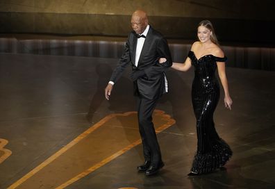 Morgan Freeman, left, and Margot Robbie are seen walking onstage at the Oscars on Sunday, March 12, 2023, at the Dolby Theatre in Los Angeles. (AP Photo/Chris Pizzello)