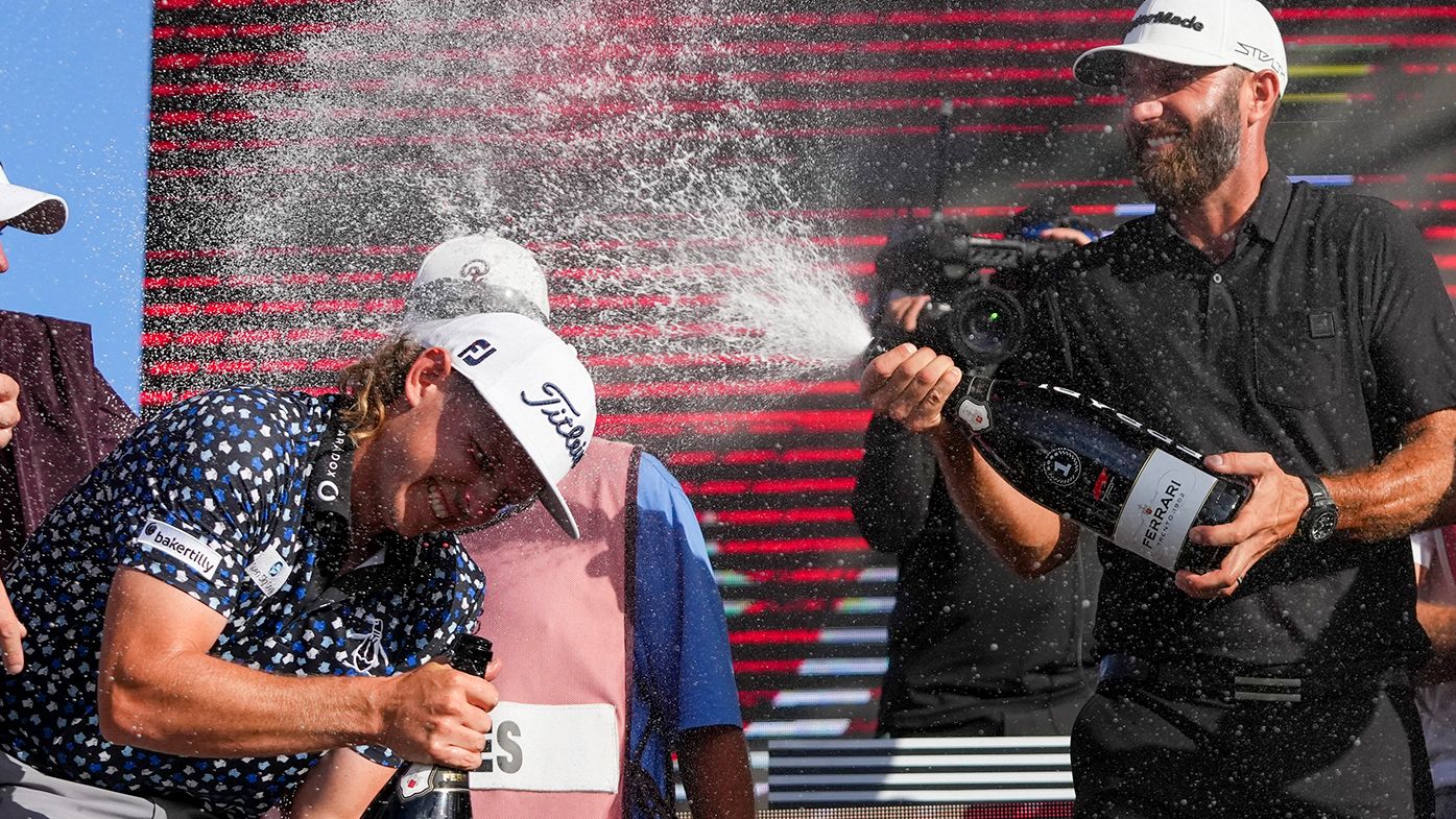 Dustin Johnson sprays champagne on Cameron Smith on the podium after the team championship stroke-play round of the LIV Golf Invitational - Miami.